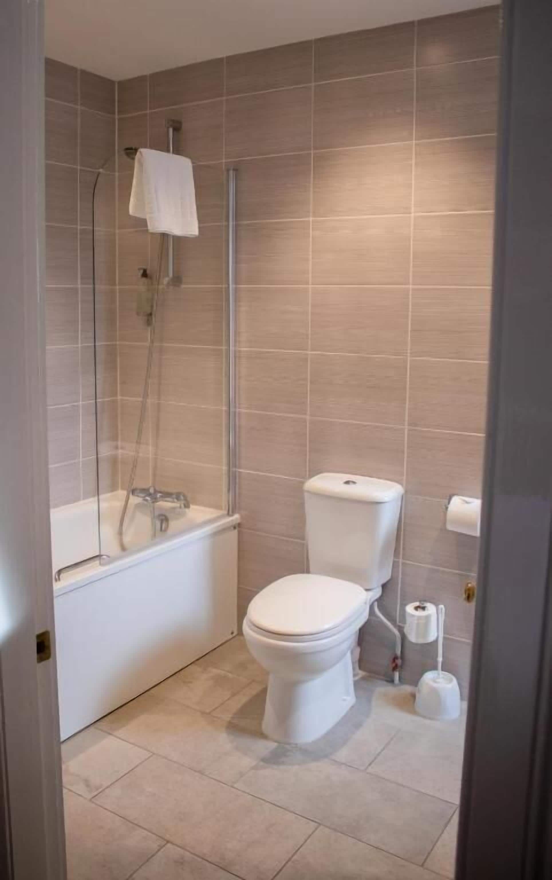 A bathroom with a bathtub, toilet, and shower.