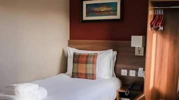 A hotel room with a bed, a desk, a chair, a wardrobe, and a painting on the wall.
