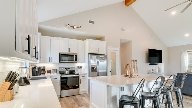 A modern kitchen with white cabinets, stainless steel appliances, and a central island with bar stools.