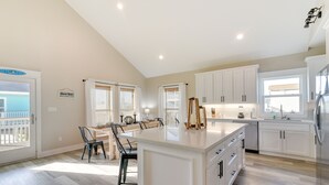 A spacious kitchen with a large island, white cabinetry, and a view of the ocean through the windows.