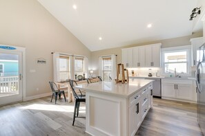 A spacious kitchen with a large island, white cabinetry, and a view of the ocean through the windows.