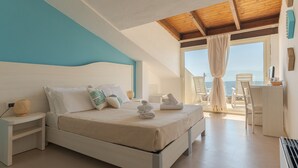 A bedroom with a bed, nightstands, a desk, and a view of the sea. - Hotel Maluentu (San Vero Milis)