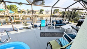 Ein überdachter Außenbereich mit Pool, Sitzgelegenheiten und Blick auf einen Yachthafen.