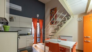 Une cuisine moderne avec des meubles blancs, une plante verte et une fenêtre ornée de rideaux orange.