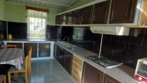 Una cocina con armarios oscuros, una mesa de comedor con sillas, una ventana con cortinas y un microondas en la encimera.