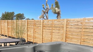 A hot tub with a control panel, surrounded by a wooden fence, and a table with chairs. - Serenity Now / Spa+Outdoor Shower+Hammocks+RV h/up (Landers)