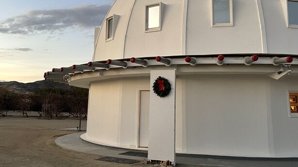 A white dome-shaped building with a door and windows, a wreath on the door, and a metal structure on the roof. - Serenity Now / Spa+Outdoor Shower+Hammocks+RV h/up (Landers)