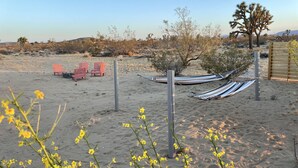 A desert landscape with a hammock, red chairs, and a wooden fence. - Serenity Now / Spa+Outdoor Shower+Hammocks+RV h/up (Landers)