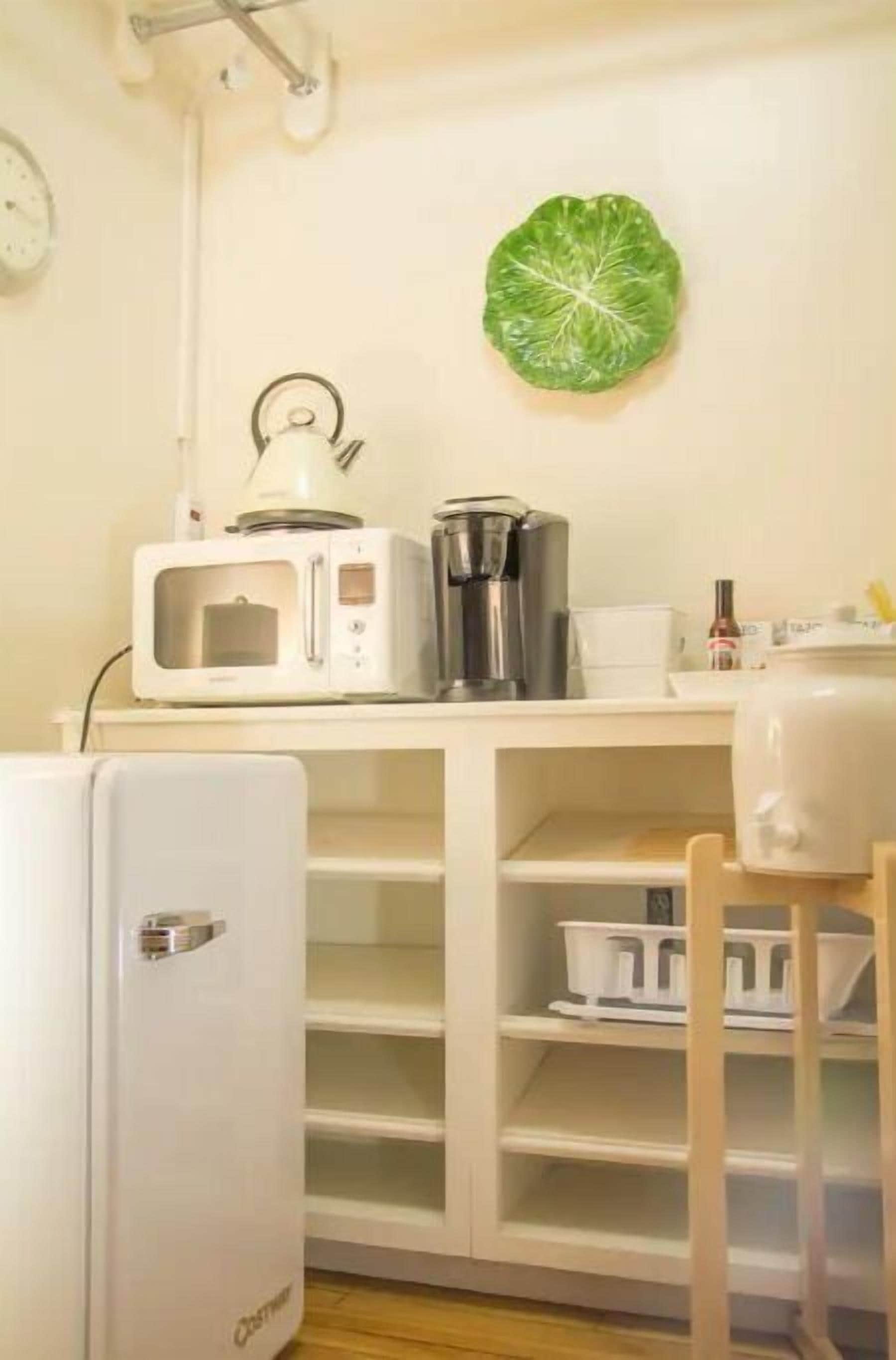 A compact kitchen with a microwave, kettle, and coffee maker on a white countertop.