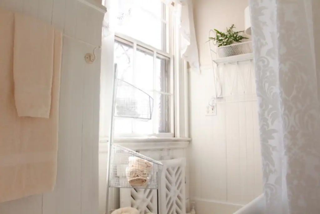 Un baño con ventana, una toalla colgada en la pared y una repisa con una planta.