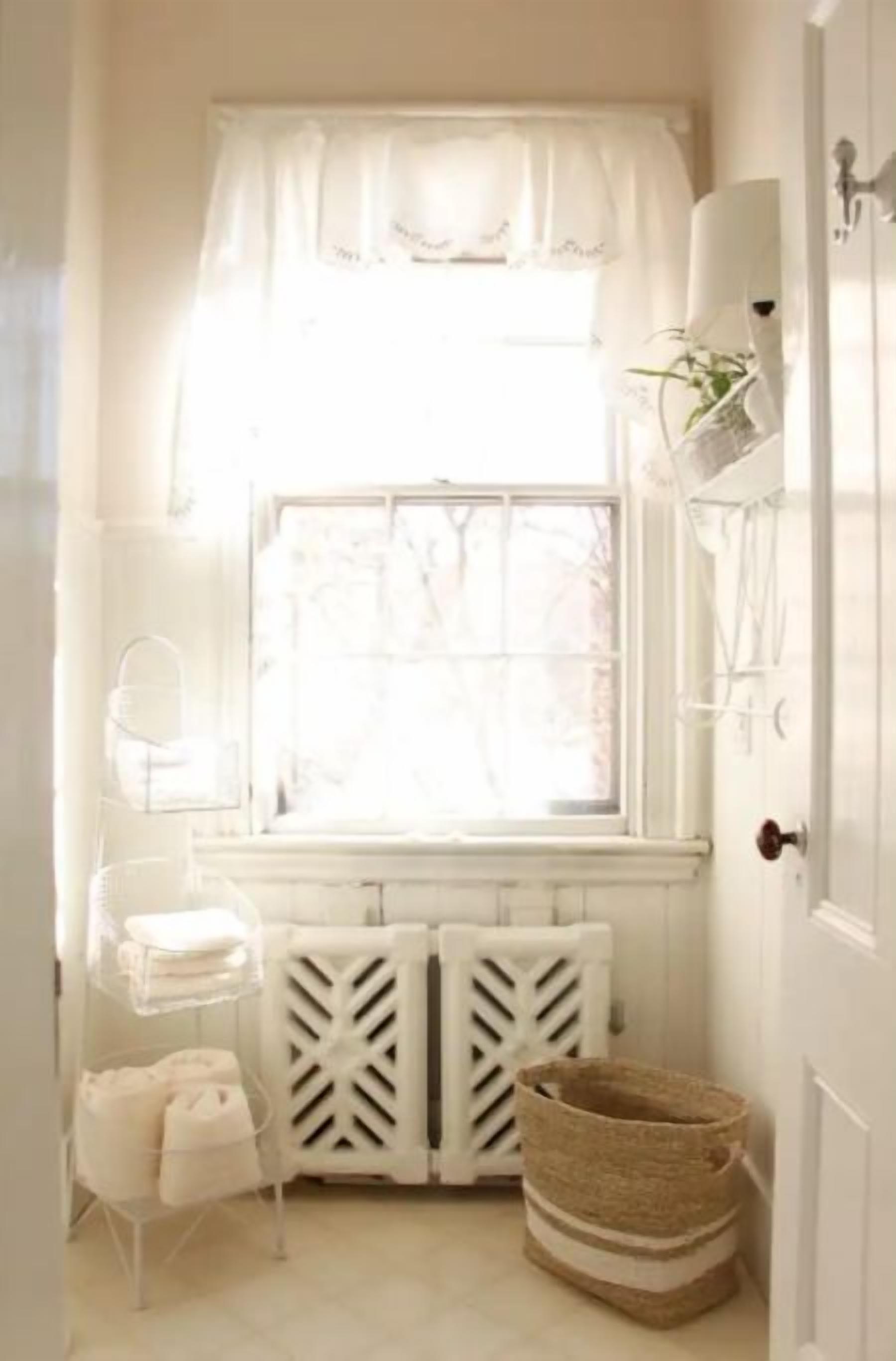 A small, bright room with a window, radiator, and a basket.