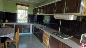 A compact kitchen with dark cabinets, a gas stove, and a microwave. - Villa Floreal 5 (floreal)