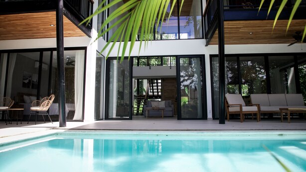 A modern house with a pool, large windows, and outdoor seating.