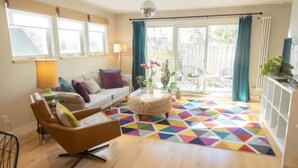 A living room with a sofa, armchair, and a colorful geometric rug. - Modern & Sunny House Steps from the Promenade. Private Parking! (Portland)