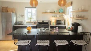 A modern kitchen with a central island, black chairs, and pendant lighting. - Modern & Sunny House Steps from the Promenade. Private Parking! (Portland)