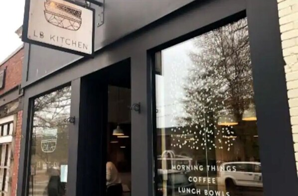 Une devanture de magasin avec une enseigne indiquant « LB KITCHEN » et une vitrine présentant une publicité pour « MORNING THINGS COFFEE LUNCH BOWLS ».