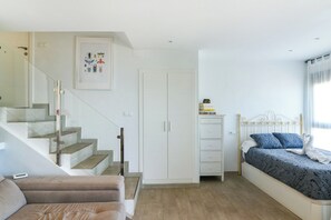 A bedroom with a bed, a wardrobe, a bedside table, and a staircase leading to an upper floor.