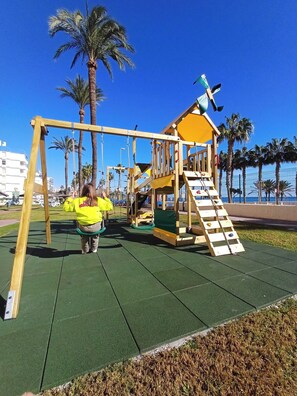 Un parque infantil con columpios y una estructura para escalar.