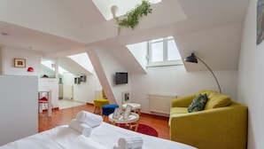 Et moderne hotelværelse med en stor seng, en gul lænestol, et lille rundt bord og et fjernsyn monteret på væggen.