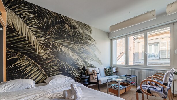 Un dormitorio con una cama grande, un sofá, una mesa de centro y vistas al exterior.