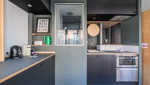 Una cocina moderna con armarios oscuros, horno integrado y ventana con vistas a la ciudad.