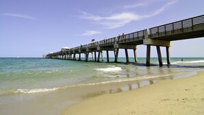 A pier extending into the ocean with a sandy beach in the foreground. - Jupiter Palms Oasis | Luxe Pool/Spa Table Tennis! (Jupiter)