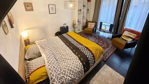 Una moderna camera d'albergo con un letto, una TV, un divano e una scrivania.