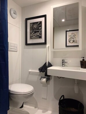 A bathroom with a toilet, a sink, a mirror, and framed pictures on the wall.