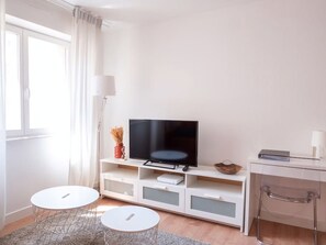 Relax in this stylish living room with a large flat-screen TV, open shelving, and comfortable seating areas.