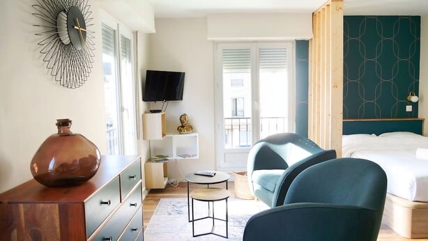 A modern hotel room with a large bed, a desk with a chair, a TV, and a decorative wall piece. - Le Cocon Urbain - Joli Studio récemment rénové (Strasbourg)