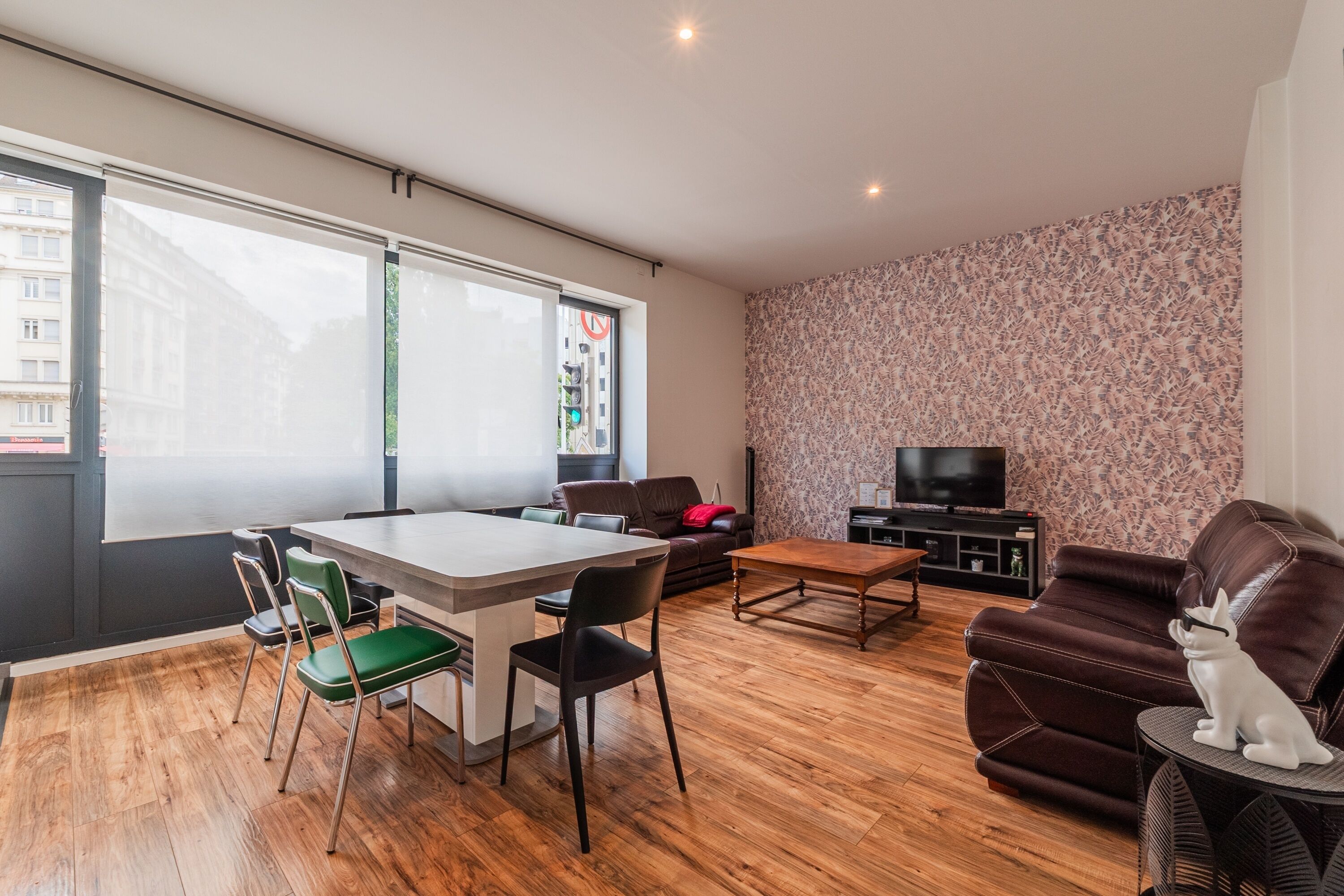 Un salon moderne comprenant une table à manger, des chaises, un canapé et un téléviseur.