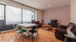 A modern living room with a dining table, chairs, a sofa, and a TV.