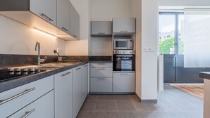 A modern kitchen with white cabinets, a stainless steel sink, and a built-in microwave.