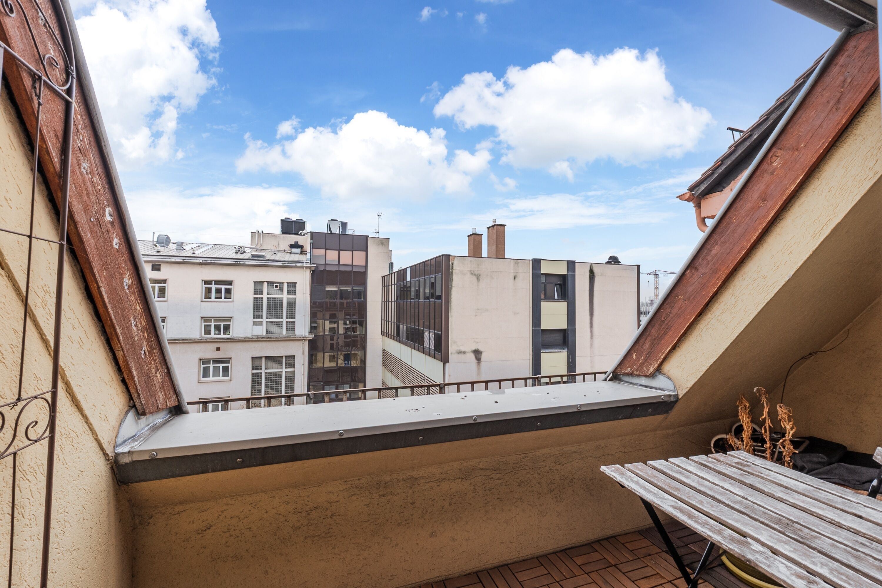 Un balcon donnant sur des immeubles, avec une table et une chaise.