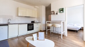 Eine moderne Küche mit weißen Schränken, einem eingebauten Backofen und einem Essbereich mit einem weißen Tisch und zwei Stühlen.