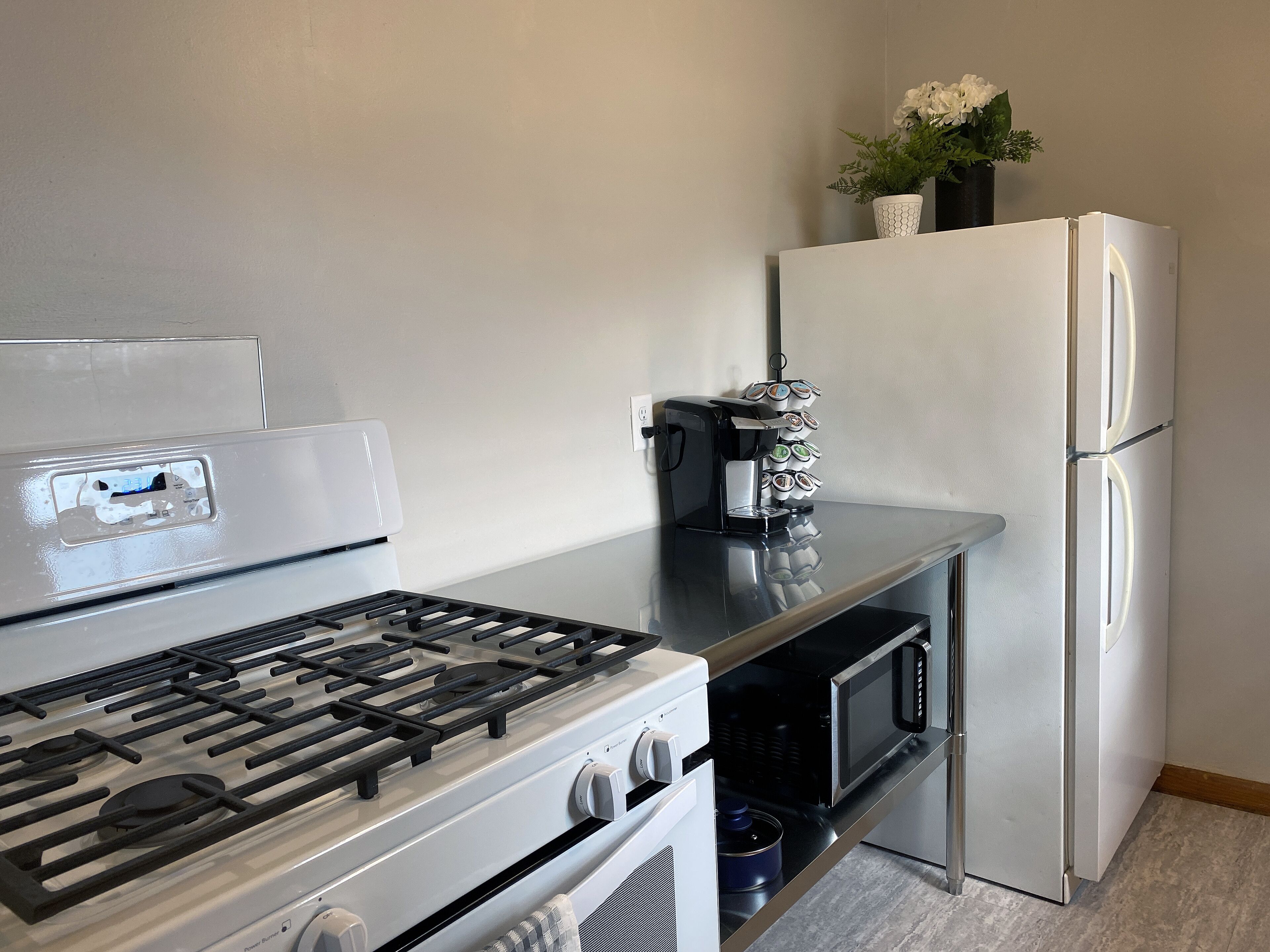 A kitchen with a gas stove, oven, microwave, and a coffee maker with a tea dispenser.