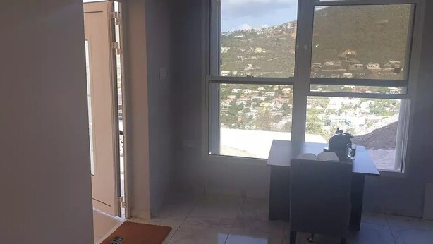 A room with a large window offering a view of a hilly landscape. - Nos Soño, Condo 3-bdr - Stunning View - Valley Verde 9, St. Maarten 2-4 Guests
 (Philipsburg)