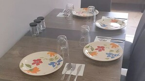 A dining table set with floral plates, clear glassware, and cutlery. - Nos Soño, Condo 3-bdr - Stunning View - Valley Verde 9, St. Maarten 2-4 Guests
 (Philipsburg)