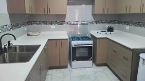A kitchen with a gas stove, oven, sink, and tiled backsplash. - Nos Soño, Condo 3-bdr - Stunning View - Valley Verde 9, St. Maarten 2-4 Guests
 (Philipsburg)