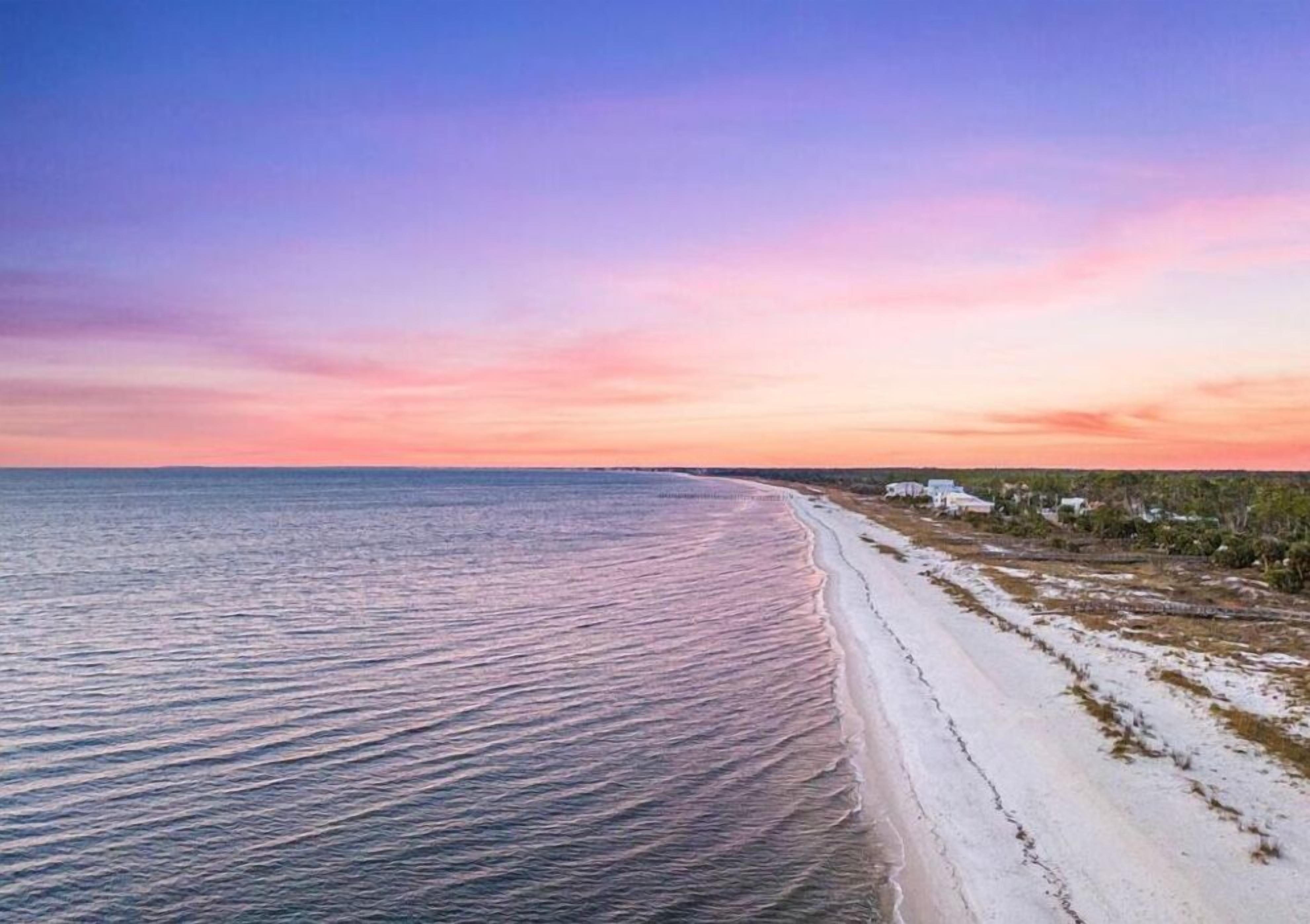 A beach with a long stretch of sand and a calm sea.