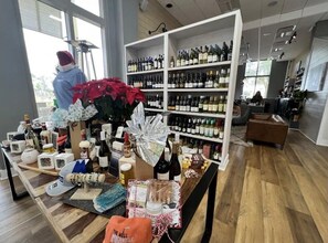 Un espai comercial amb prestatges plens de diverses ampolles, una taula expositora amb articles diversos i una persona amb barret de Pare Noel treballant a una estació.
