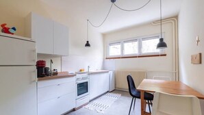 A modern kitchen with white cabinets, a wooden countertop, a built-in oven, and a dining area with a wooden table and chairs.