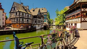 A canal-side view with traditional half-timbered buildings, a bicycle, and a bridge.