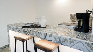 A kitchen with a patterned backsplash, a coffee machine, and bar stools. - Linda Vecindad Playa del Carmen (Playa del Carmen)