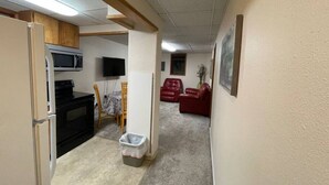 A compact living space with a kitchenette, a dining area, and a seating area with red sofas. - 305 2bd Lower · Moose 2 bedroom lower, close to downtown (Fairbanks)