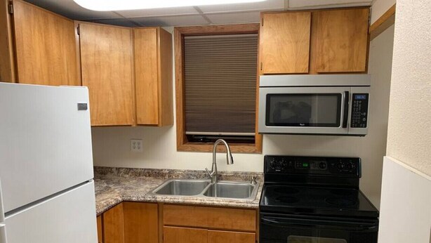 A compact kitchen with wooden cabinets, a double sink, a microwave, and a stove. - 305 2bd Lower · Moose 2 bedroom lower, close to downtown (Fairbanks)