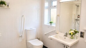 A bathroom with a toilet, a sink, a mirror, and a window. - Lodge 6 - Lytton Tree Lodge - Reydon (Reydon)