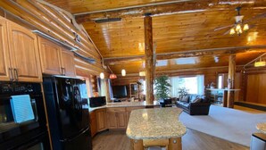 A kitchen with wooden cabinets, a granite countertop, and a black stove. - 2010 Steese Hwy · Aurora viewing, quiet space, entire log home (Fairbanks)