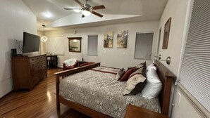 A bedroom with a bed, wooden dresser, desk, and a ceiling fan. - R & R Hideaway Suite (Fairbanks)