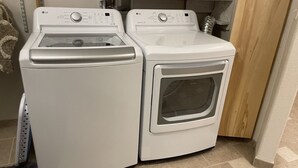 A compact, white front-loading washer and dryer unit with a control panel on top. - R & R Hideaway Suite (Fairbanks)